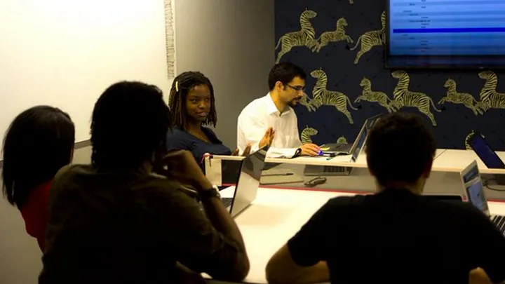 photo of a group of 5 people working on a project at a hackathon in a conference room with their laptops
