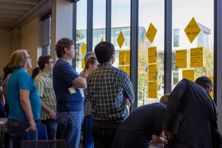 group of people looking at post-it notes organized on a window